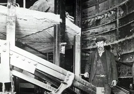 Two workmen stand with the spiral escalator at Holloway Road station; image courtesy of London Transport Museum.