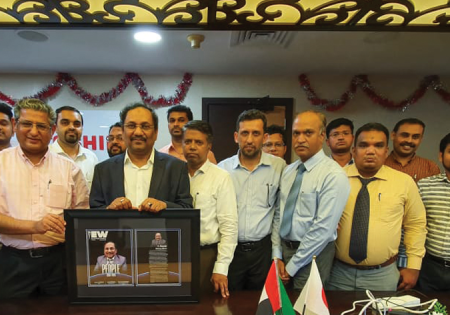 Iqbal, third from left, holds a framed copy of the ELEVATOR WORLD June 2020 People Issue feature about him.