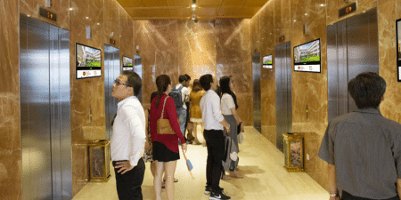 Watching advertisements while waiting for the elevator is common among many office workers and residents; image courtesy of Chicilon.